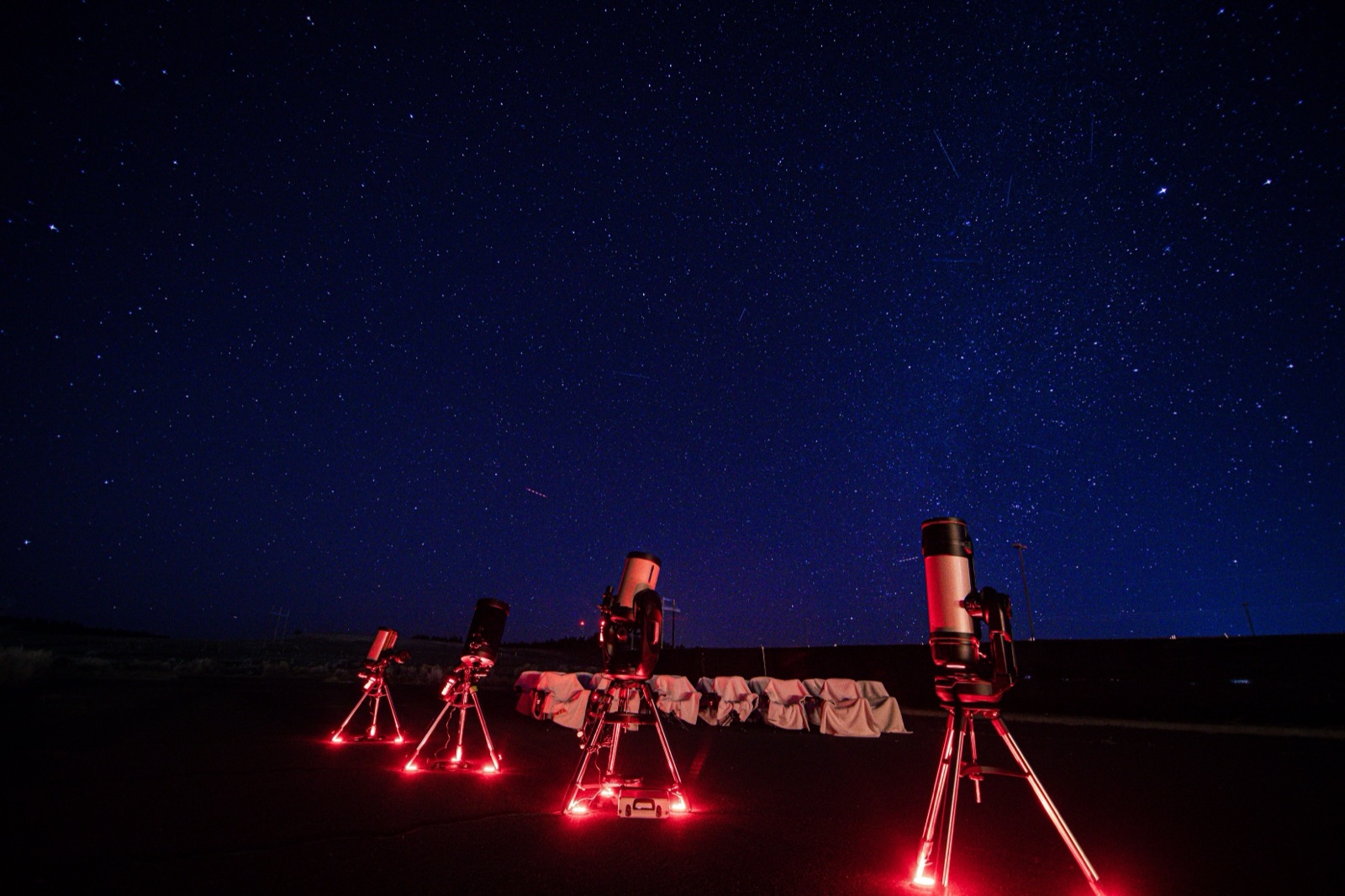 Four telescopes set up under red night-vision lighting beneath a star-filled sky on a Bryce Canyon Stargazing tour